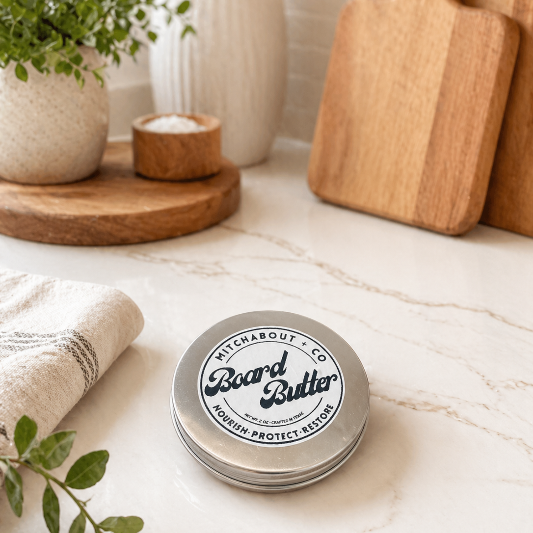 Two-ounce tin of Mitchabout + Co Board Butter wood conditioner on a marble kitchen counter